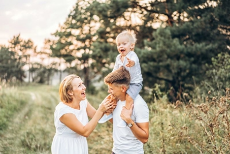 A smiling family stands in a field.