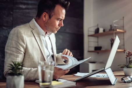 A professional man in a suit reviews documents at a desk.