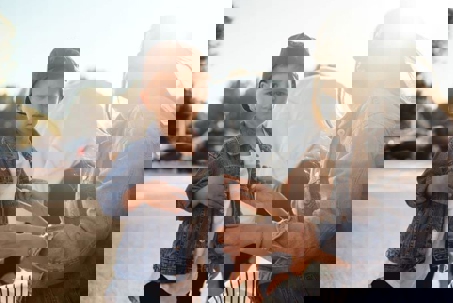 A young boy stands in a denim jacket, while a woman helps him