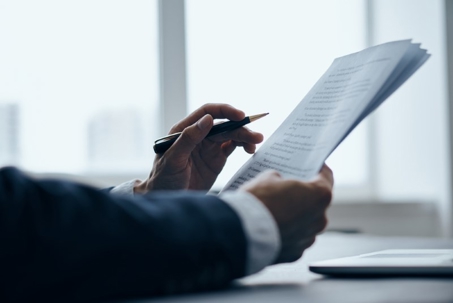 a person reviewing a document with a pen in hand.