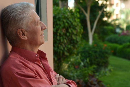 An older man in a red shirt stands outside, enjoying the scenery